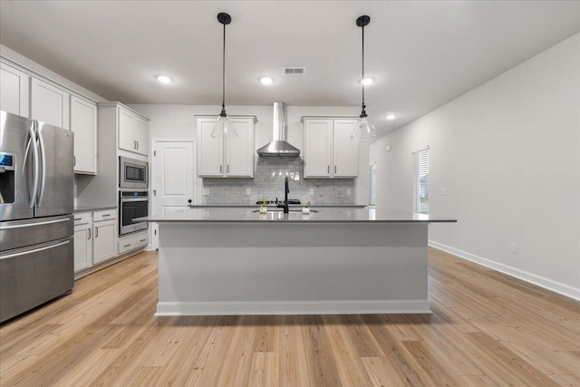 kitchen featuring pendant lighting, white cabinets, wall chimney range hood, and appliances with stainless steel finishes