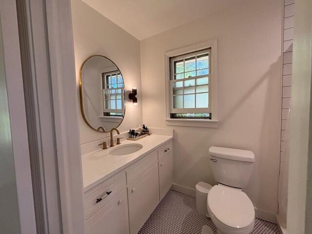 bathroom featuring baseboards, tile patterned floors, toilet, and vanity