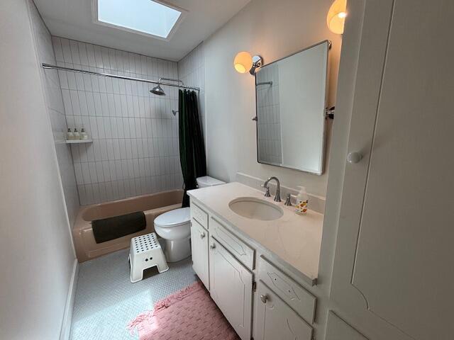bathroom with a skylight, vanity, shower / bathtub combination with curtain, and toilet