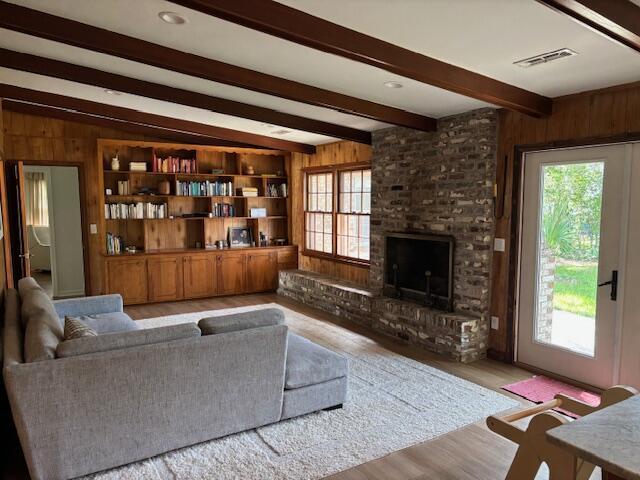 living room featuring visible vents, wood finished floors, wooden walls, and a healthy amount of sunlight