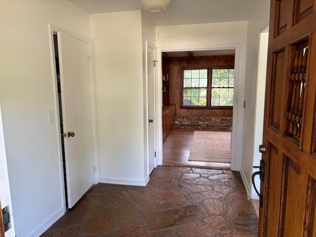 corridor featuring baseboards and stone finish floor
