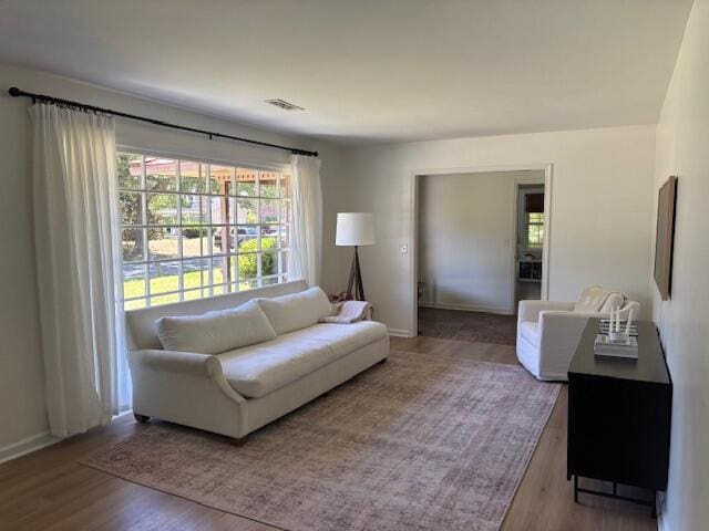 living area with baseboards, visible vents, and wood finished floors