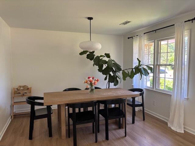 dining area with light wood-style floors, baseboards, and visible vents