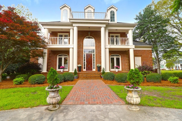 neoclassical home featuring a balcony and brick siding