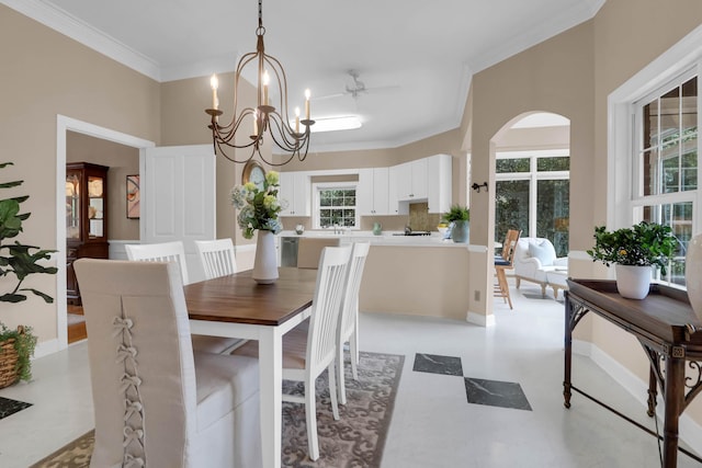 dining space with arched walkways, ornamental molding, ceiling fan with notable chandelier, and light floors