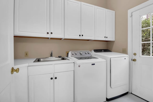 clothes washing area with washing machine and dryer, cabinet space, and a sink