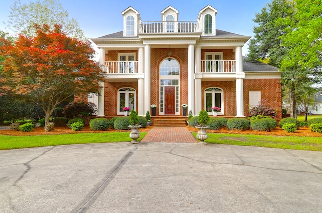 greek revival inspired property featuring a balcony, brick siding, and french doors