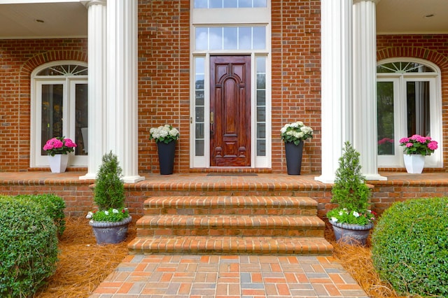 doorway to property with covered porch and brick siding
