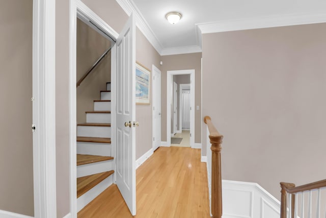 stairway with a wainscoted wall, ornamental molding, and wood finished floors