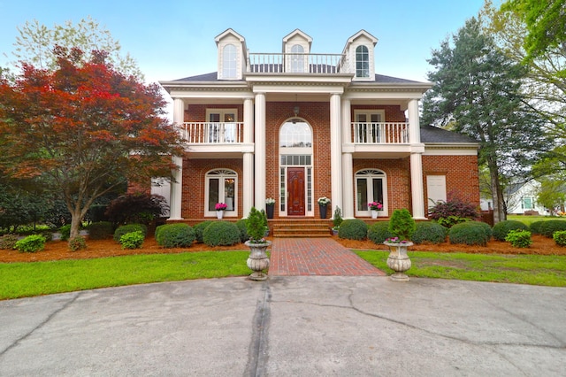 greek revival house featuring french doors, a balcony, and brick siding