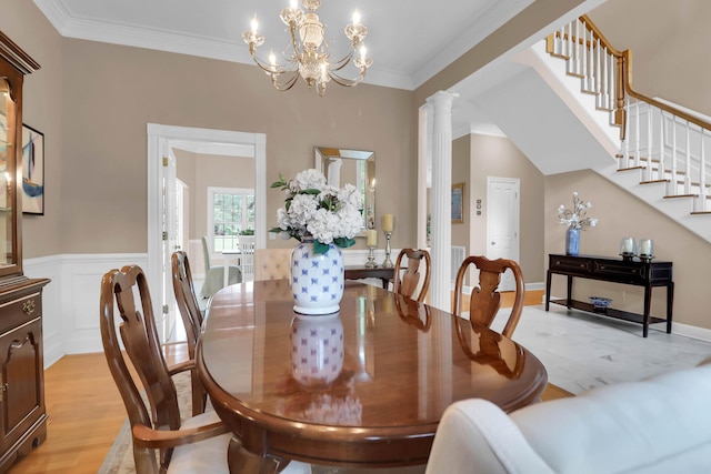 dining area featuring a notable chandelier, light wood-style flooring, wainscoting, and ornamental molding