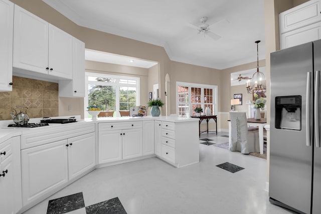 kitchen featuring backsplash, light countertops, stainless steel fridge, and a peninsula