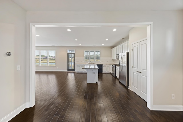 kitchen featuring white cabinetry, a center island, tasteful backsplash, dark hardwood / wood-style flooring, and appliances with stainless steel finishes