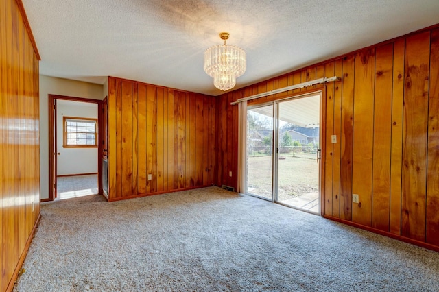 unfurnished room featuring a textured ceiling, light carpet, and a wealth of natural light