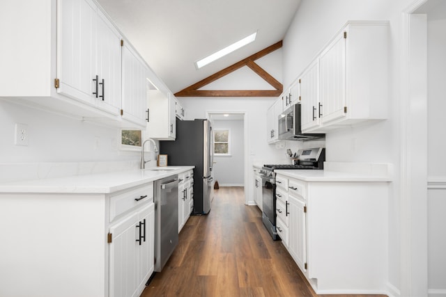 kitchen with sink, plenty of natural light, vaulted ceiling, white cabinets, and appliances with stainless steel finishes