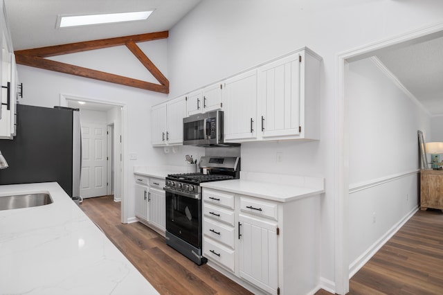 kitchen with light stone countertops, dark hardwood / wood-style floors, lofted ceiling, white cabinets, and appliances with stainless steel finishes