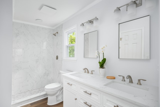 bathroom featuring a tile shower, toilet, hardwood / wood-style flooring, vanity, and ornamental molding