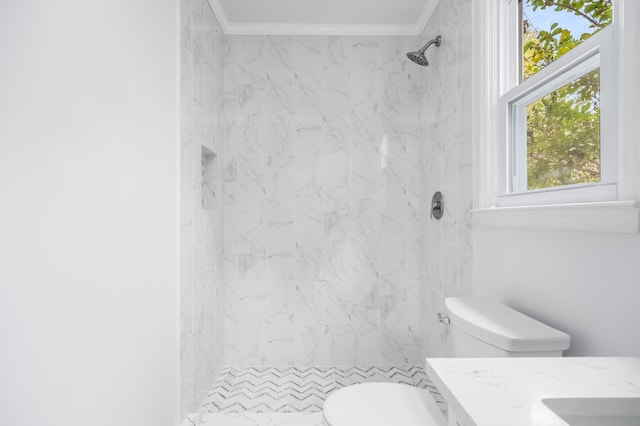 bathroom featuring tiled shower, toilet, vanity, and ornamental molding