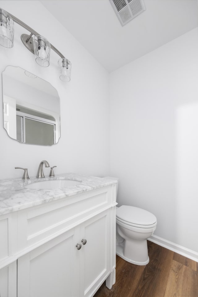 bathroom featuring hardwood / wood-style floors, vanity, toilet, and walk in shower