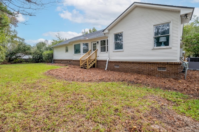 rear view of house featuring a lawn and central AC