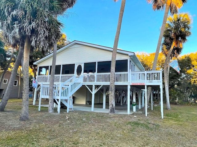 rear view of property featuring a sunroom, a yard, and a patio area