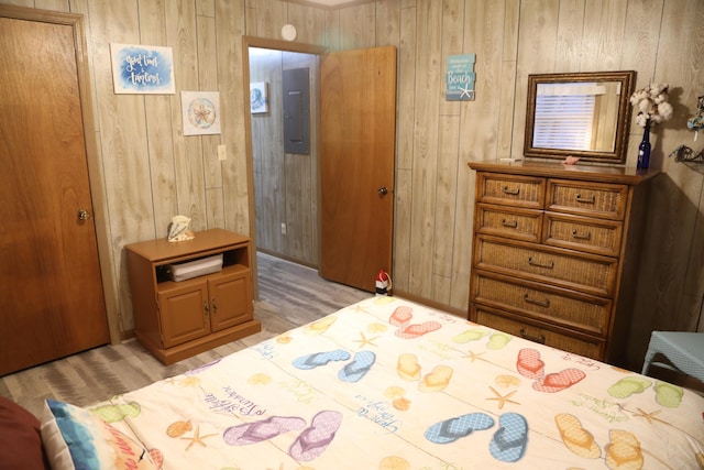 bedroom with wooden walls, light hardwood / wood-style floors, and electric panel