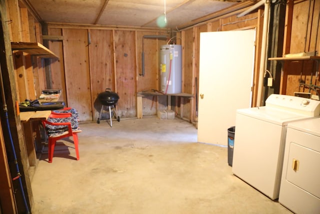 basement with wooden walls, washing machine and dryer, and water heater