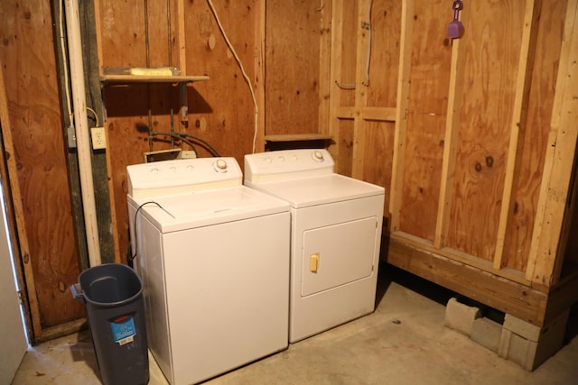 washroom featuring washing machine and dryer and wood walls