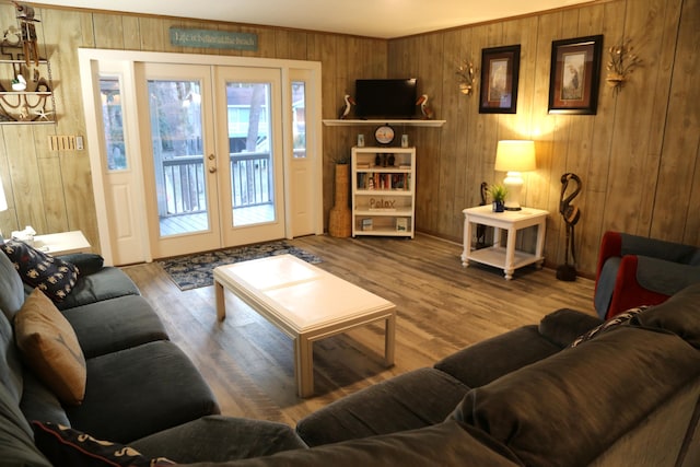 living room with hardwood / wood-style flooring, wooden walls, ornamental molding, and french doors