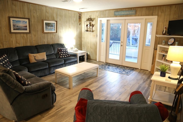 living room with wood-type flooring, wood walls, and french doors