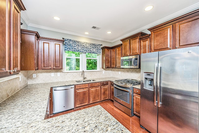 1253 Dingle Rd, Mount Pleasant, SC 29466 - kitchen with stainless steel appliances, light wood-style floors, light stone countertops, crown molding, and backsplash