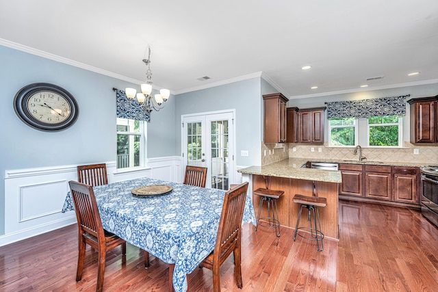 1253 Dingle Rd, Mount Pleasant, SC 29466 - dining area featuring french doors, dark wood-style floors, a chandelier, a wainscoted wall, and crown molding