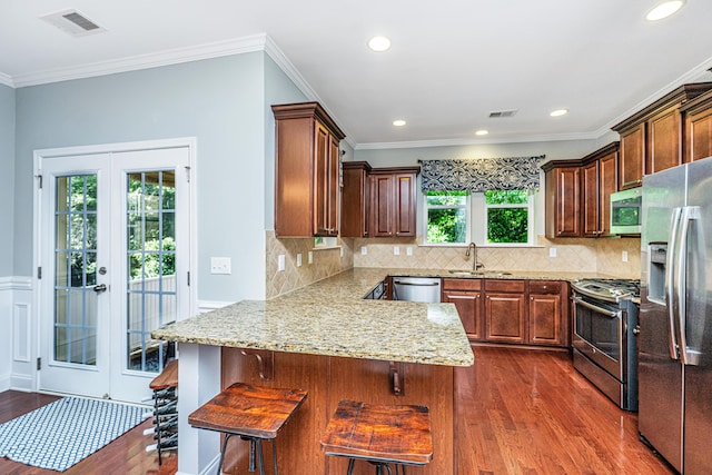 1253 Dingle Rd, Mount Pleasant, SC 29466 - kitchen featuring stainless steel appliances, a peninsula, dark wood-style flooring, french doors, and a kitchen breakfast bar