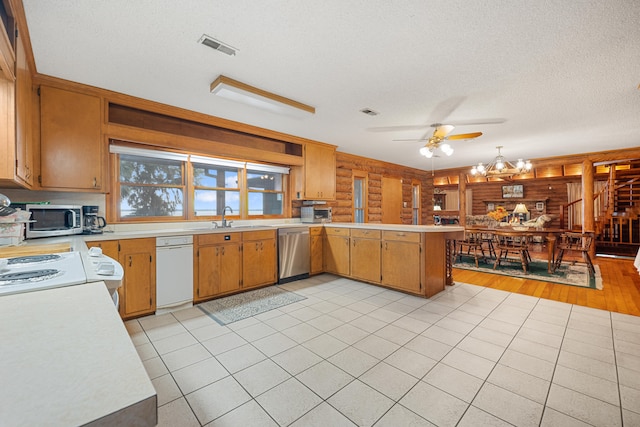 kitchen with stainless steel appliances, kitchen peninsula, wood walls, light hardwood / wood-style floors, and a textured ceiling