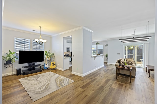 living room featuring wood-type flooring, crown molding, and an inviting chandelier