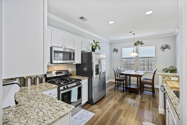 kitchen featuring light stone countertops, appliances with stainless steel finishes, backsplash, decorative light fixtures, and white cabinets