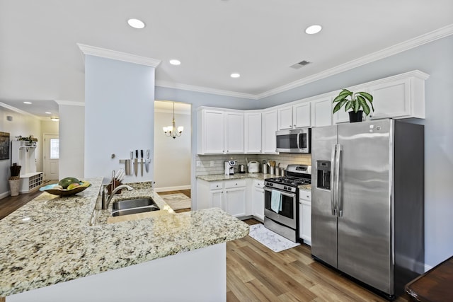 kitchen featuring kitchen peninsula, stainless steel appliances, sink, decorative light fixtures, and white cabinets