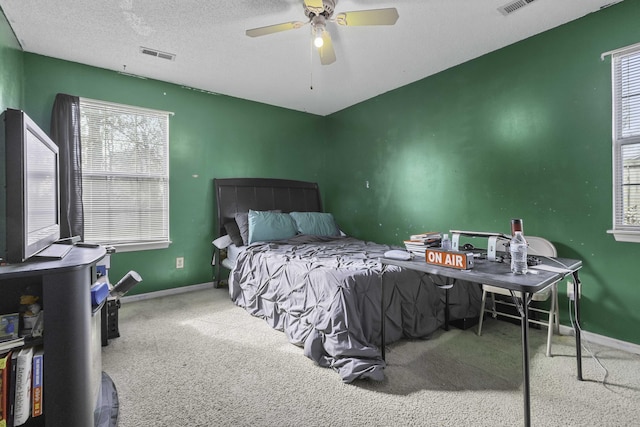 carpeted bedroom with ceiling fan and a textured ceiling