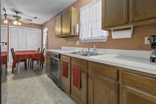 kitchen with ceiling fan, black dishwasher, sink, and a textured ceiling