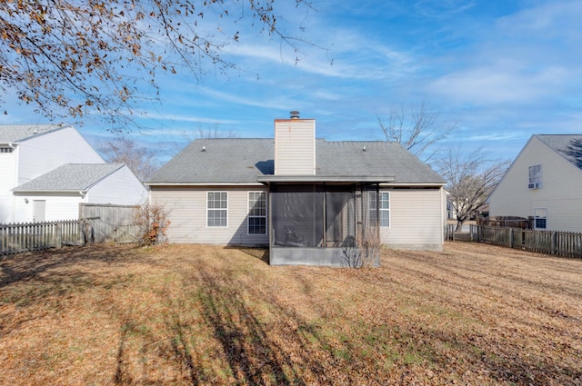 rear view of house featuring a lawn and a sunroom