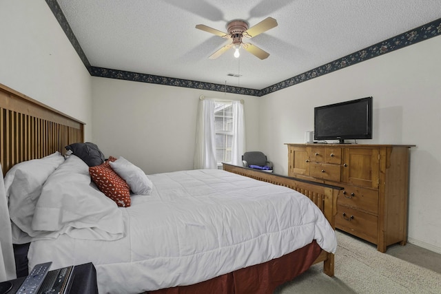 carpeted bedroom with ceiling fan and a textured ceiling