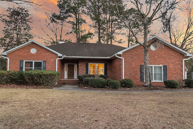 single story home featuring a chimney, a front lawn, and brick siding