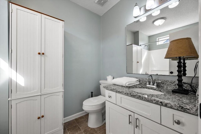 bathroom featuring visible vents, vanity, toilet, and a textured ceiling