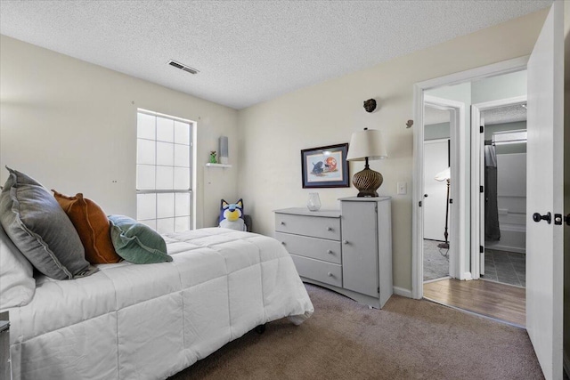 carpeted bedroom featuring a textured ceiling and visible vents