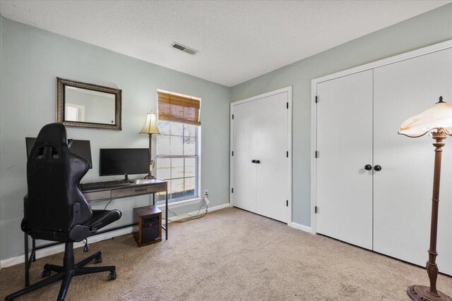 carpeted office space with visible vents, a textured ceiling, and baseboards