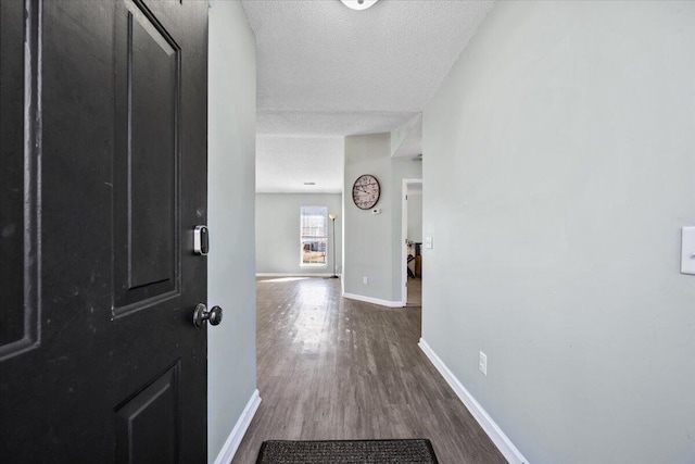 interior space featuring dark wood-style floors, baseboards, and a textured ceiling