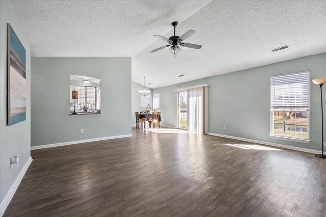 unfurnished living room with visible vents, vaulted ceiling, wood finished floors, and ceiling fan with notable chandelier