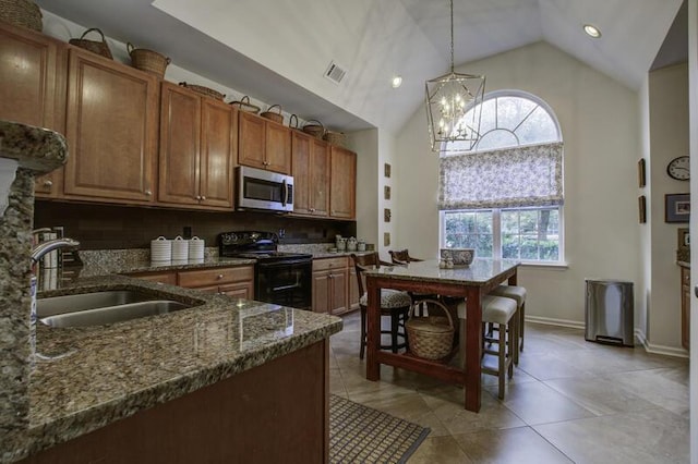 kitchen featuring dark stone counters, sink, pendant lighting, electric range, and a notable chandelier