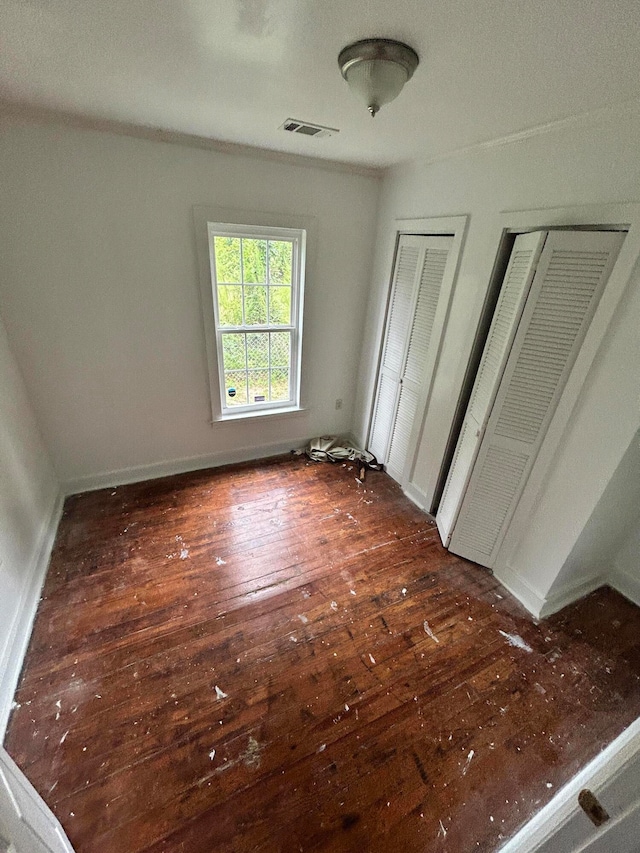 unfurnished bedroom featuring multiple closets and dark hardwood / wood-style flooring