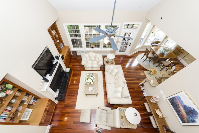 living room with a high ceiling, ceiling fan, a wealth of natural light, and dark hardwood / wood-style floors